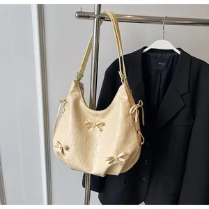 Detailed view of cream yellow tote bag featuring soft pleated leather and bow accents