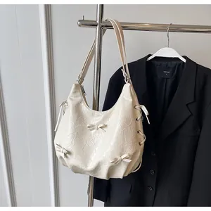 Detailed close-up of cream pleated leather tote with decorative 3D bow and drawstring