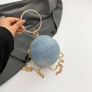 Light blue spherical evening bag with rhinestones and round gold handle held by hand