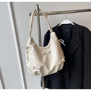 Detail of cream hobo bag with pleated texture and decorative small ribbon bows