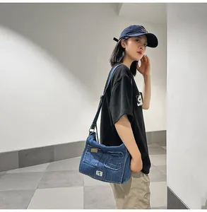 Detail of blue denim crossbody bag with embossed letter C and metallic buckle on a model