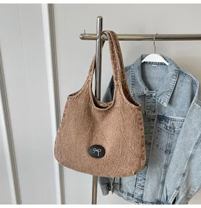Macro shot of durable brown washed denim tote with silver metal bow patch and thick texture