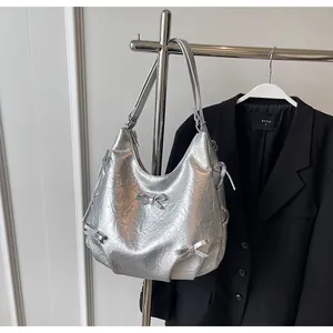 Detail of silver metallic hobo bag featuring crinkled texture and 3D ribbon bows