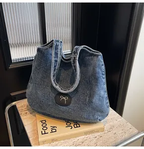 Detail of blue denim tote bag with circular leather butterfly patch on a lifestyle background