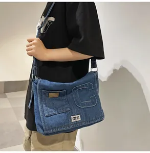 Detail of dark blue denim shoulder bag with embossed letter C and silver twist lock closure