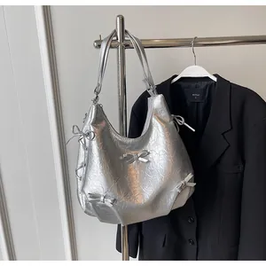 Detail of silver metallic hobo bag with multiple bow ties and wrinkled leather texture