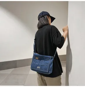 Blue denim crossbody bag featuring large C patch and adjustable strap worn by model