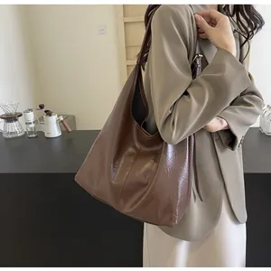 Vue latérale d'un grand cabas en cuir marron foncé porté par un mannequin avec élégance
