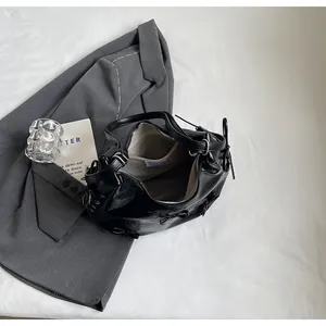 Close-up of black glossy tote bag with bow details, zip closure and inner pocket