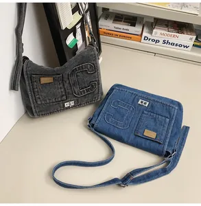 Detail of blue and grey washed denim shoulder bags with metal twist lock and C stitching