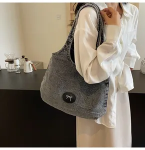 Side view of charcoal grey washed denim tote bag with chic bow logo in cafe setting