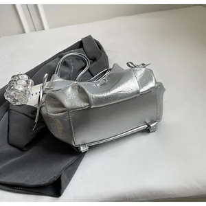 Detail of silver metallic tote bag featuring pleated texture and side bow decorations