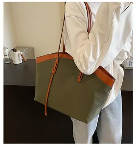 Detail shot of a large olive green canvas tote bag with brown leather handles and straps