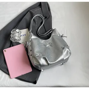 Detail of silver metallic tote bag featuring ribbon bows and side lace-up design
