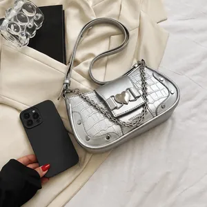 Detail of a silver crocodile pattern underarm bag with a heart buckle
