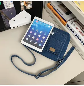 Deep blue denim crossbody bag showing large capacity by holding a white tablet