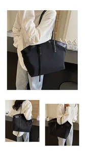 Detail of a large black tote bag with leather trim and slim shoulder straps for daily use