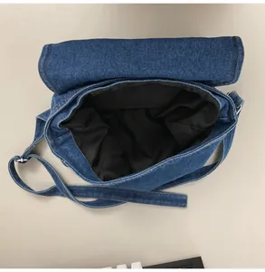 Detail view of denim crossbody bag interior with black lining and adjustable strap
