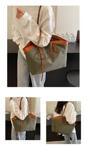 Detail of olive canvas tote bag with brown leather handles and large capacity design