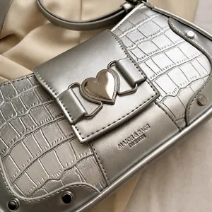 Detail of silver crocodile pattern texture with heart buckle and metal rivets