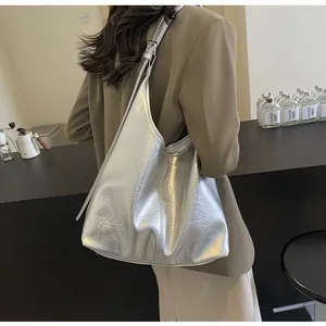 Gros plan sur la texture en cuir argenté froissé et le fini métallique du grand sac cabas