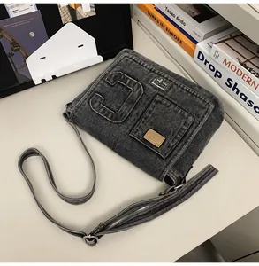 Macro shot of dark grey denim crossbody bag featuring a stitched C and metal lock