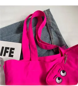 Detail of neon pink tote bag featuring monster eye embroidery and reinforced handle stitching