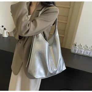 Détail du grand sac cabas argenté montrant sa texture plissée métallique sur un mannequin