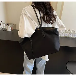 Close-up of a black canvas and leather trim tote bag on a model shoulder for daily use
