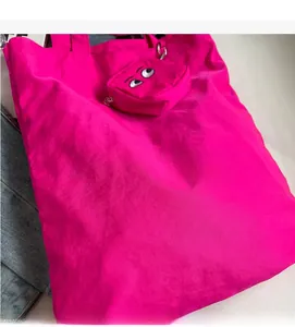 Macro detail of magenta nylon tote bag with cartoon eye embroidery and soft fabric texture