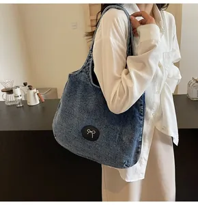 Side view of a vintage blue denim tote bag with a white bow patch on a model