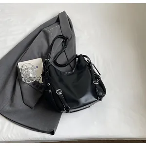 Detail of minimalist black PU leather tote with silver metal hardware and side tie design