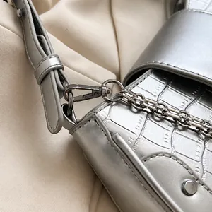 Detail of silver crocodile pattern leather handbag with polished metallic hardware