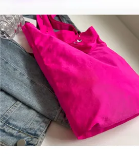 Close-up of pink foldable monster tote bag with cartoon eye pouch on white table