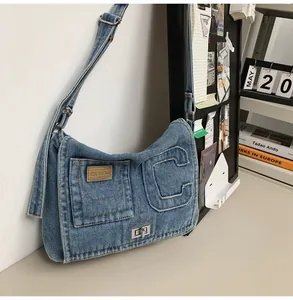 Detail of blue washed denim shoulder bag featuring a silver twist lock and letter C patch