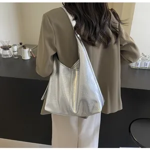 Sac fourre-tout argenté à texture froissée porté à l'épaule par un mannequin chic