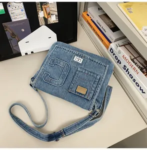 Detail of light blue denim crossbody bag with embossed letter C and metal twist lock closure