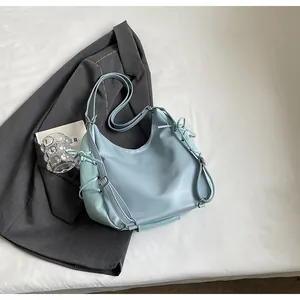 Close-up of light blue leather crescent bag with decorative side drawstrings and silver buckle