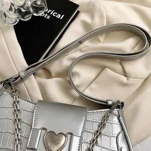 Detail of silver crocodile pattern bag featuring adjustable strap and metallic chain