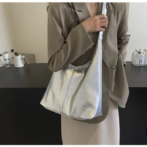 Détail du sac hobo argenté métallisé avec texture plissée réfléchissante sur comptoir