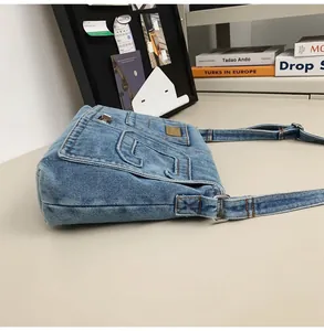 Detail of blue washed denim bag with metal buckles on a minimalist art studio desk