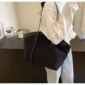 Detail of a large black tote bag featuring leather trim and long drawstring accents