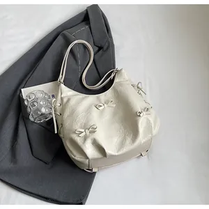 Detail view of cream-colored tote bag with bow decorations and pleated texture