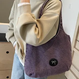Large vintage washed denim tote bag in purple with silver bow detail worn by model