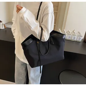 Detailed view of black nylon tote bag with leather trim worn by a model in a casual setting