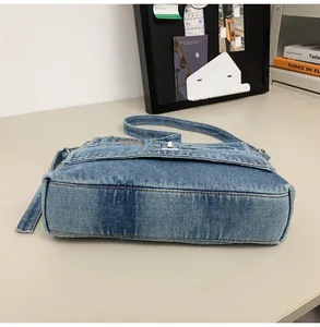 Detailed close-up of light blue washed denim shoulder bag showing silver metal turn-lock