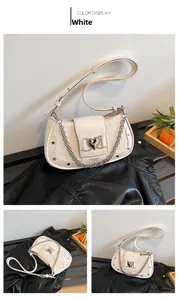 Close-up of white crocodile pattern shoulder bag with silver heart buckle and chain detail