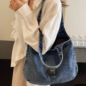 Large denim tote bag in dark blue wash featuring a white bow accent and leather patch