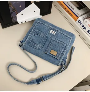 Close-up of blue denim shoulder bag with letter C patch and silver metal twist lock