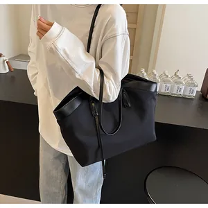 Detailed view of black nylon and leather tote bag styled with casual white sweatshirt